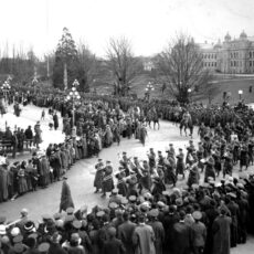This is a black and white photograph of World War I troops marching past the Legislative buildings in Victoria, BC in 1915.