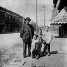 This is a black and white photograph of a father with his three children on Cormorant Street in Victoria, BC.