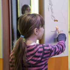 This is a photograph of a girl pressing a button on one of the welcoming panels at the Our Living Languages exhibition.