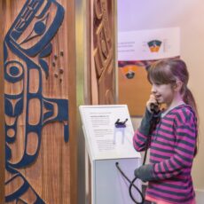 This is a photograph of a girl holding a receiver at the Interactive Light Pillar at the Our Living Languages exhibition.