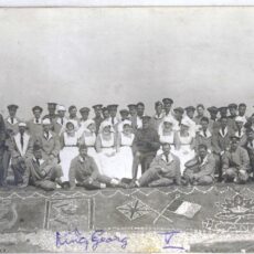 This is a black and white image of a group of nurses and soldiers in front of pictures made with pebbles.