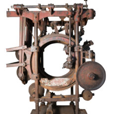 A large iron structure consisting of a series of wheels, gears and levers. The large centre wheel is perforated.