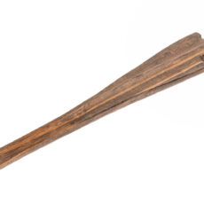 A 60 cm (two feet) long stick. The stick is slightly wider and thicker at one end in the rough shape of a handle, and tapers down to a narrow end. At the narrow end there is a small white stone or bone projecting out about half a centimetre. There is a groove carved down the middle that goes from the bone projectile to the handle shape. On the backside of the handle end there is a small indentation for a finger to fit into.
