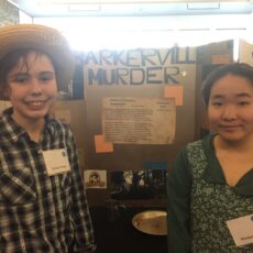 Two students posing in front of a school project about Barkerville, BC.