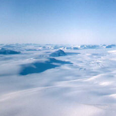 Blue sky above frozen mountain tops covered with snow and ice.