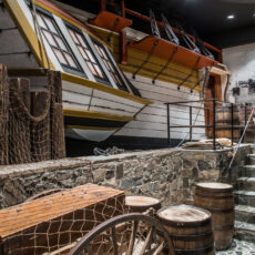 Replica of Captain Vancouver’s ship HMS Discovery. Stone steps lead up to the ship which is surrounded by barrels and supplies.