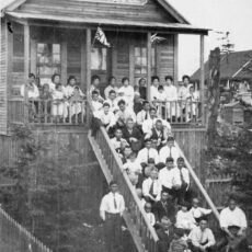 A large group of people, including children, on the steps of a building with a sign that says “Japanese Temple”.