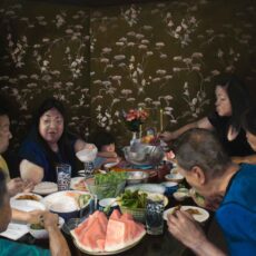 Oil painting of a Vietnamese Canadian family having a traditional dinner. There is a family altar at the end of the table with fruit.