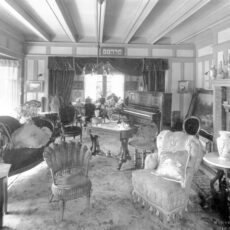 Inside an ornate living room with many chairs and a piano.